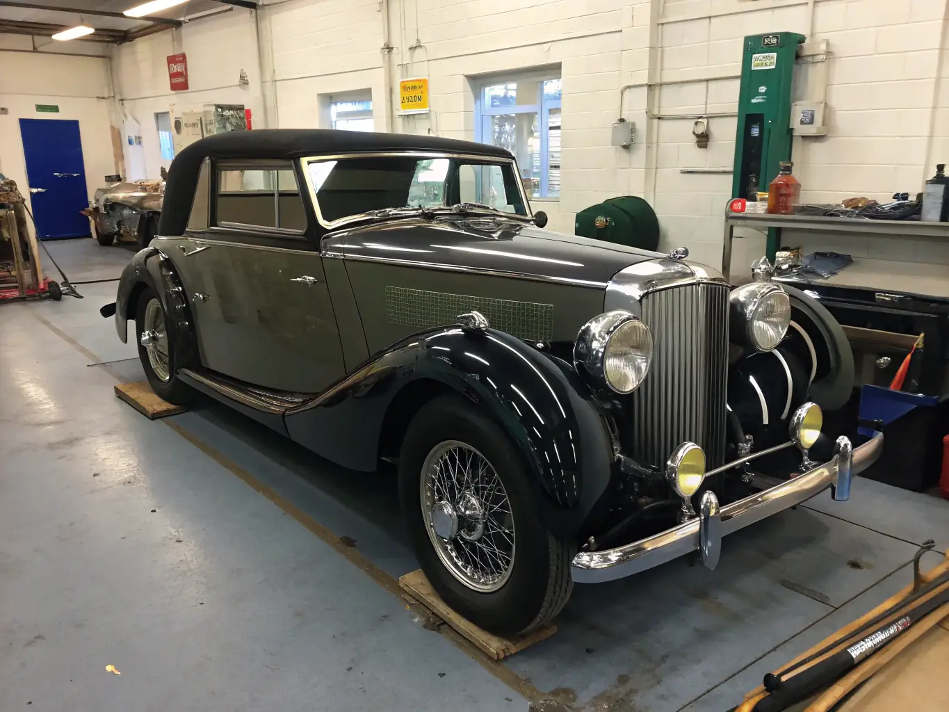 A meticulously restored vintage race car, gleaming under workshop lights, with mechanics carefully examining its engine. The scene captures the dedication and precision involved in preserving automotive history.